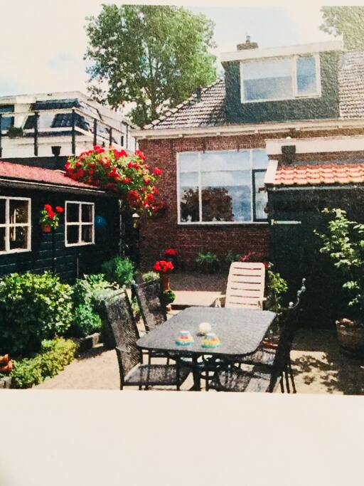 De achtertuin in zomertooi gezien vanaf het terras aan het water