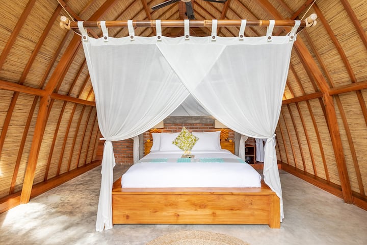 Cozy queen sized bed in the first floor right under the arched natural grass roof.