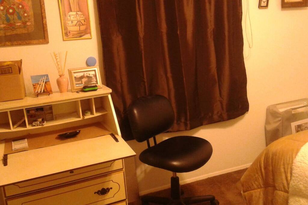 Bedroom w fliptop desk and drawers , comfortable desk chair and southwest decor .
