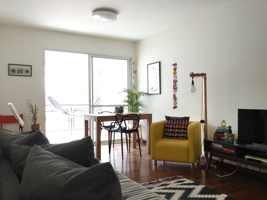 This is our sunny living and dining room equipped with a comfortable sofabed, TV, table, many books and a balcony with a "rede"