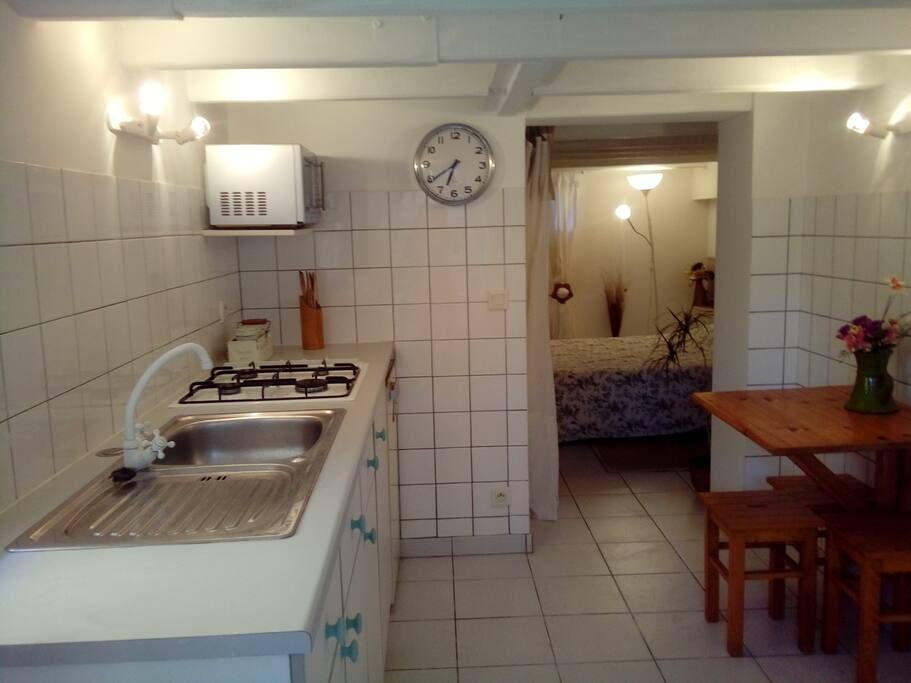Cuisine équipée d'une gazinière, réfrigérateur, micro-onde, cafetière, grille-pain et vaisselle.