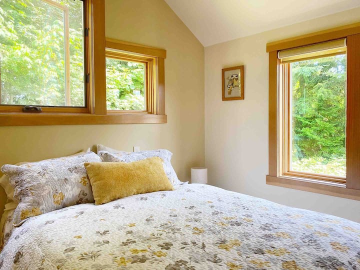 Owl’s Nest has one very private bedroom with a queen bed, closet space, and three large drawers for storing your belongings. The windows look out over trees and a grassy area. 