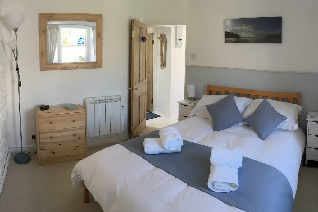 Double bedroom with original granite wall, walk-in wardrobe, chest of drawers, bed-side cabinets and lights. Sash window over-looking decking area.