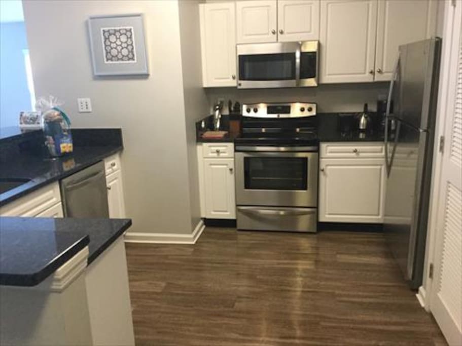 Fully equipped kitchen with stainless steel appliances, pots, pans and dishes