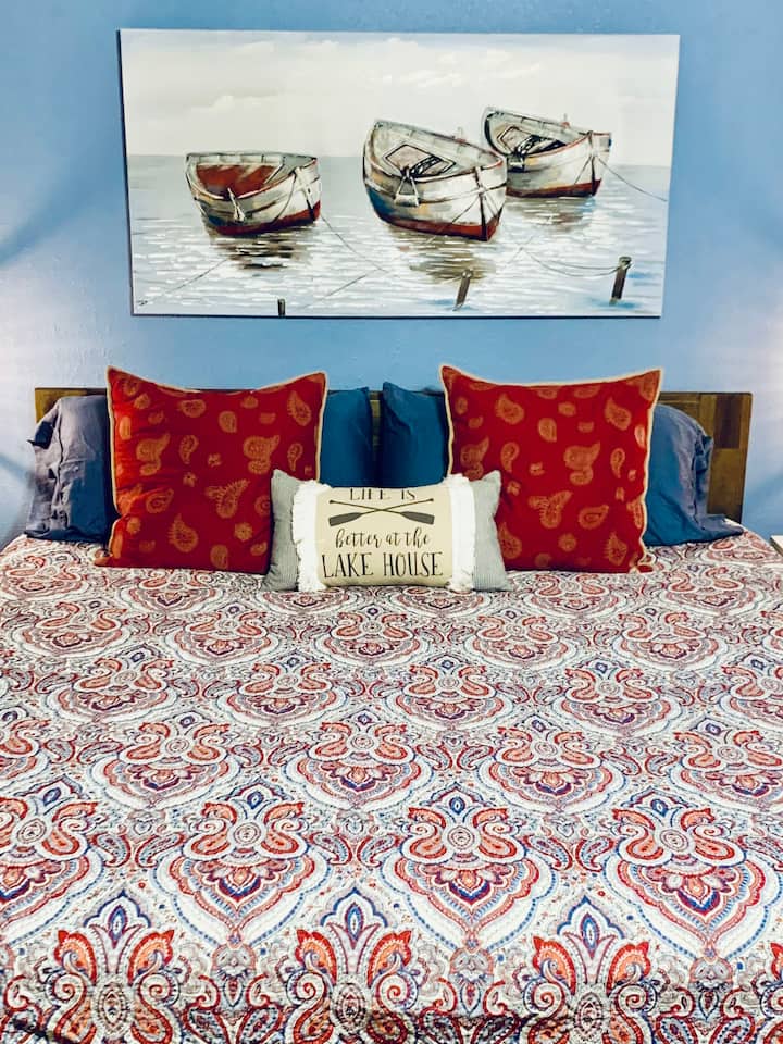 חדר השינה הראשי הגדול המשקיף על האגם, ממוקם למעלה עם מיטת קינג סייז, פוטון בגודל מלא ומיטת יחיד.  