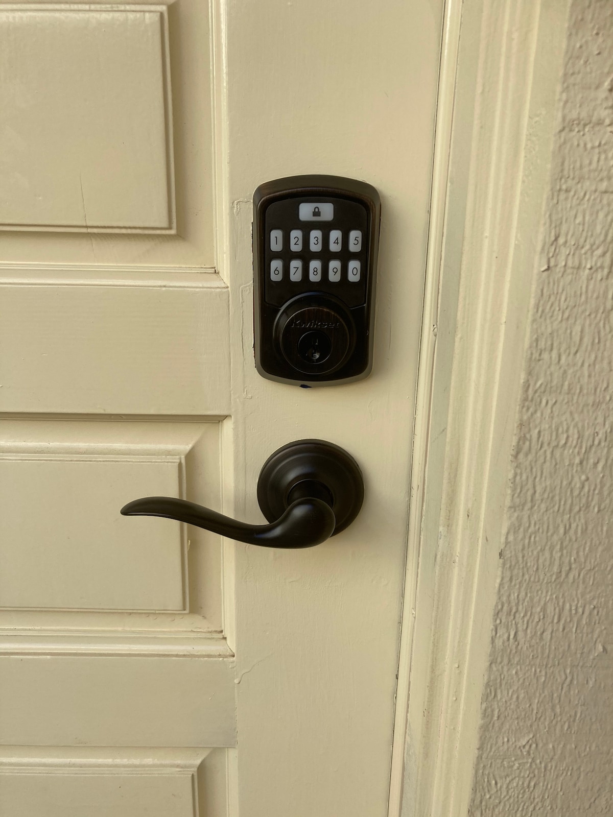 A keyless entry system is mounted beside a door, featuring a numeric keypad for access. The door handle is dark in color, complementing the subtle beige of the door panel. The door's design includes horizontal grooves, enhancing its classic appeal.