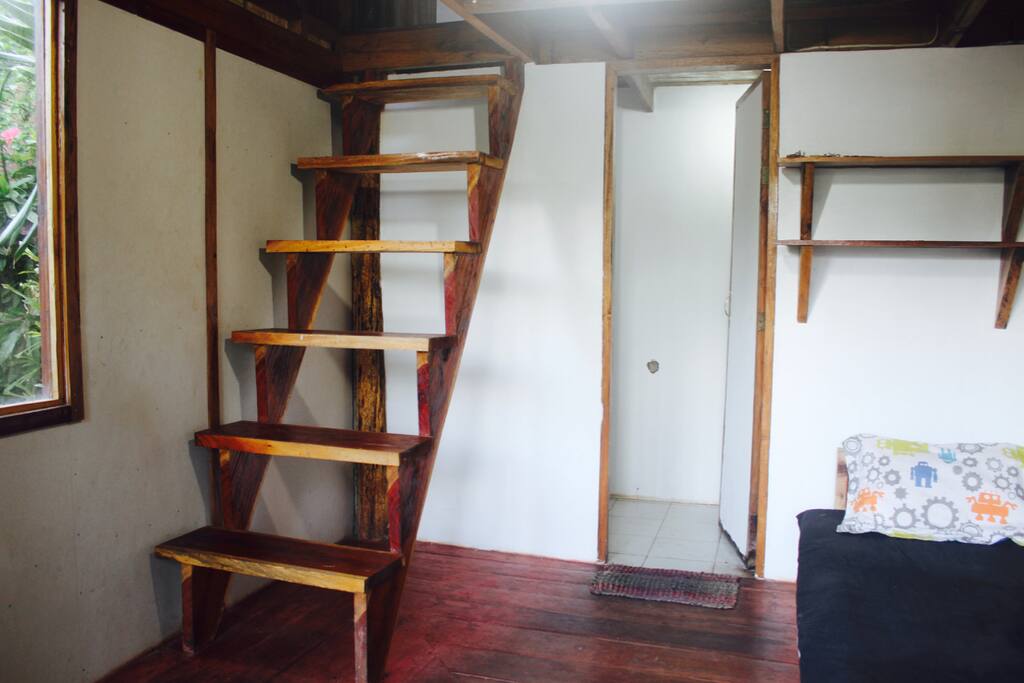 A simple private bathroom with a small, single bed downstairs.