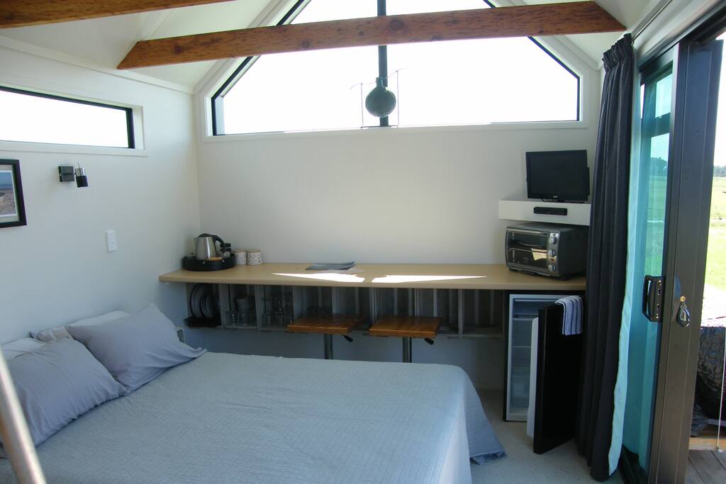 Main living room with queen bed, bench, fridge, cooking facilities and TV, DVD player.