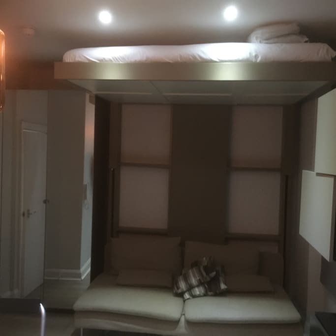 Two seater sofa on the ground with high ceilings bed hanging on the air during the daytime !!!!