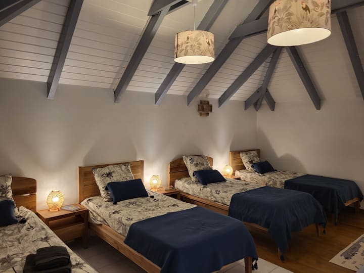 Dortoir climatisé sur mezzanine avec 4 lits et matelas 90 cm x 190 cm.
Placard ouvert avec étagères et penderie.