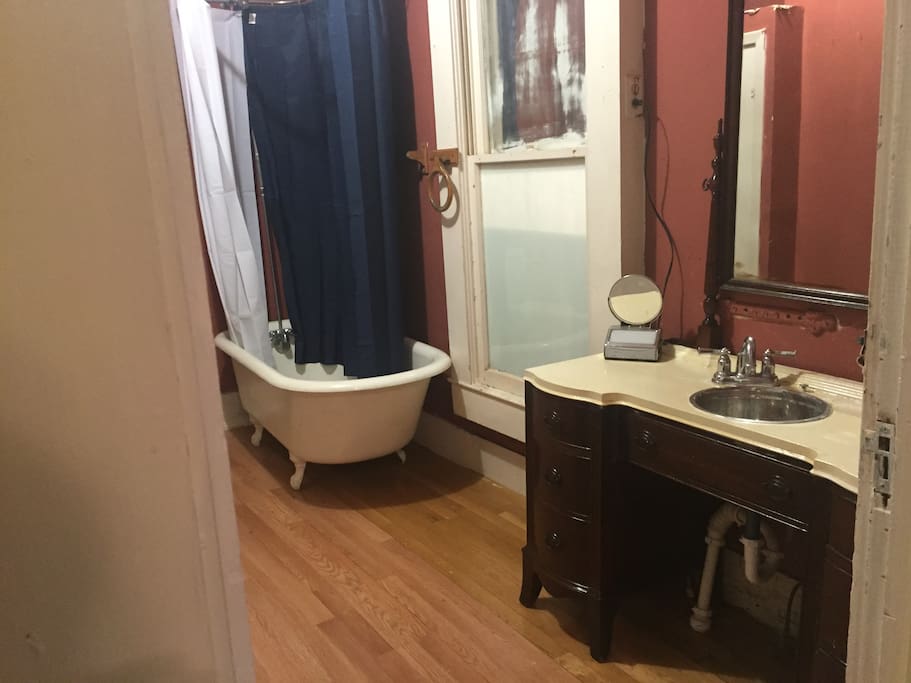 Antique claw foot tub and period vanity sink with drawers. Roomy bathroom with modern 17" toilet.