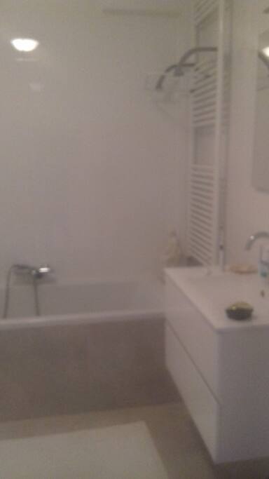 De badkamer heeft een bad en een douche