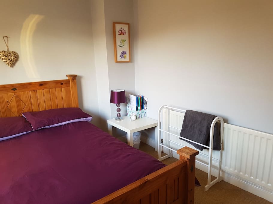 Double bed with side table and towel rack.