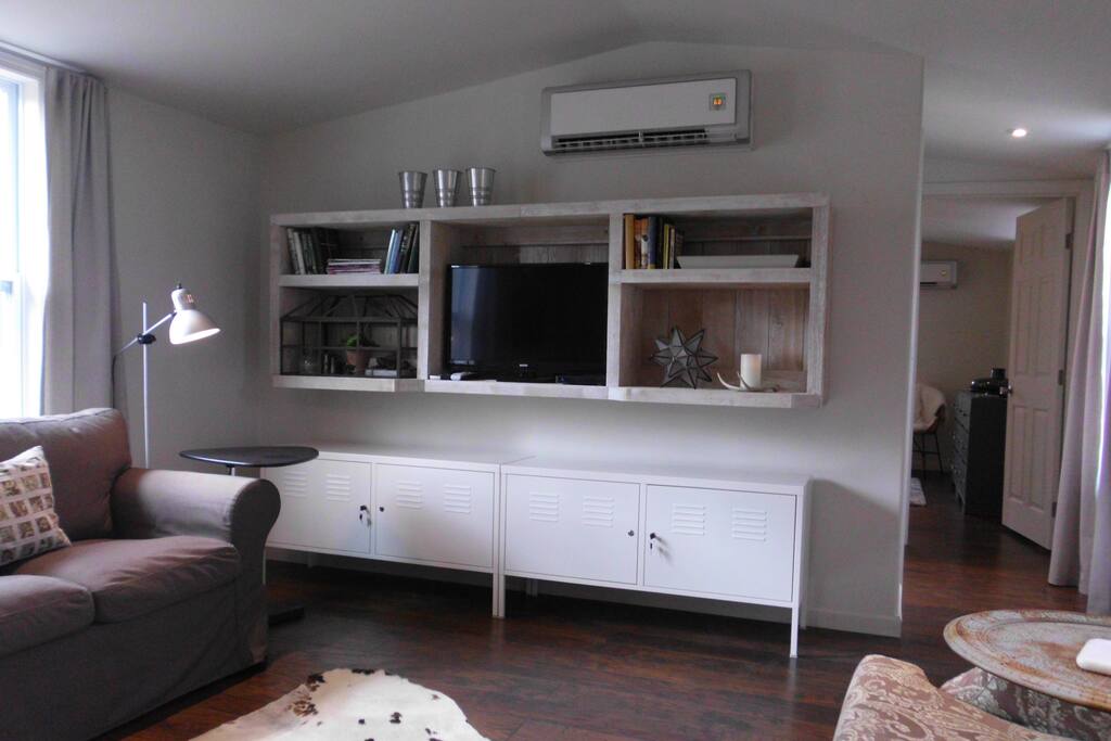Living room with wall mounted DirecTV and WiFi. Ductless H/AC unit visible above.