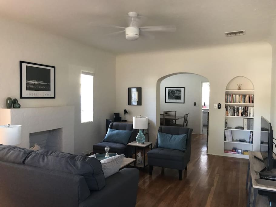 Living room with comfortable seating, reading material, desk and television.
