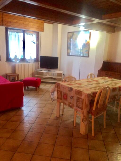 Salotto con ampio tavolo da 4, TV e divano letto. Due finestre.