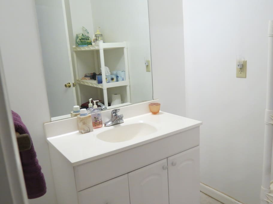 Bathroom sink separated by door from toilet and shower.
