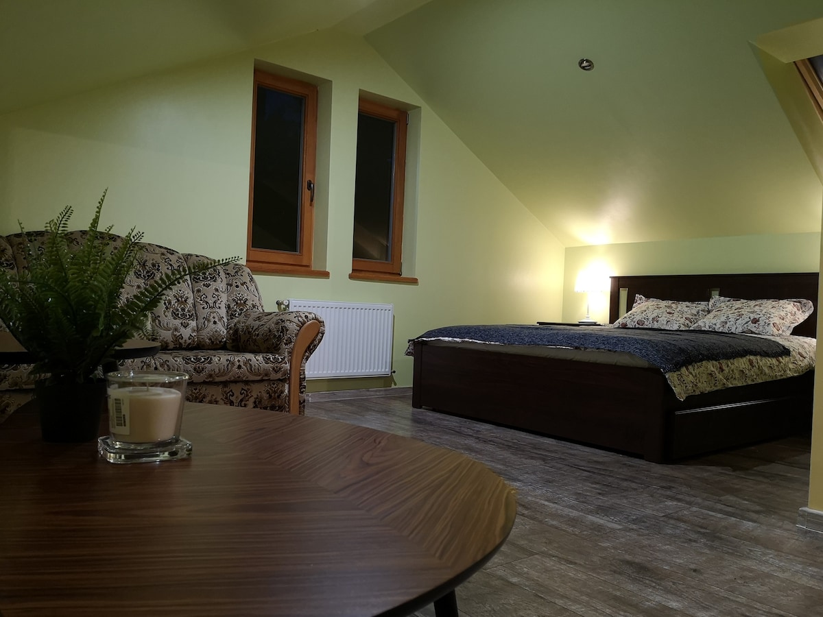 חדר שינה עם מיטה זוגית וספה בקומה השנייה.