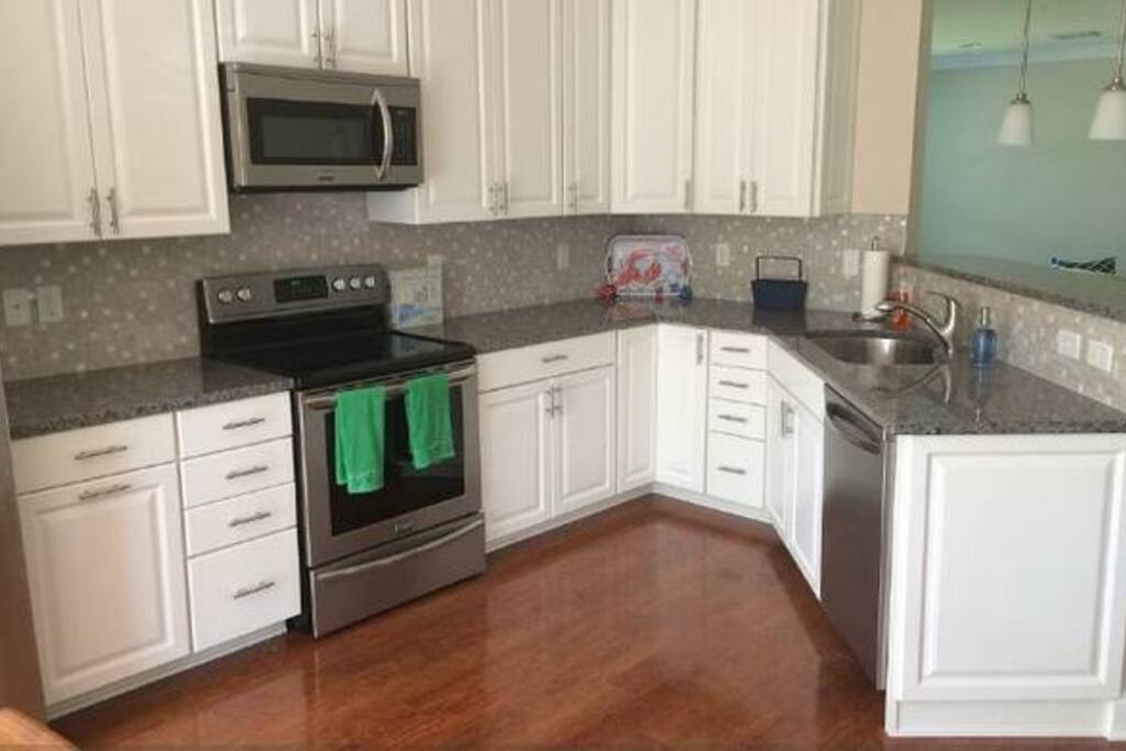 Both kitchens feature the same gorgeous white kitchen with stainless steel appliances and coastal backdrop. Comes with everything you need! (76 Pictured)