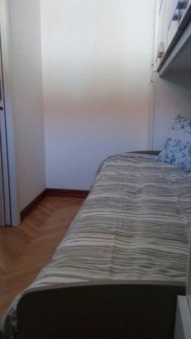 Cameretta singola con armadio e letto a ponte.