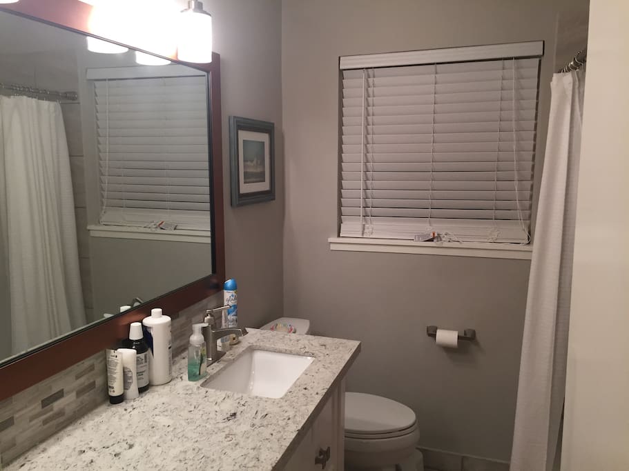 Shared bathroom with large vanity, shower with tub, and hairdryer, shampoo, conditioner, etc for your use - no need to bring travel size toiletries.