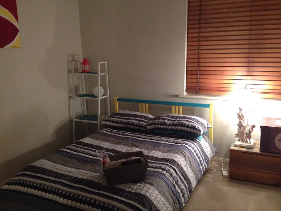 Double bed with bedside ladder shelving and light. Photo taken at night.