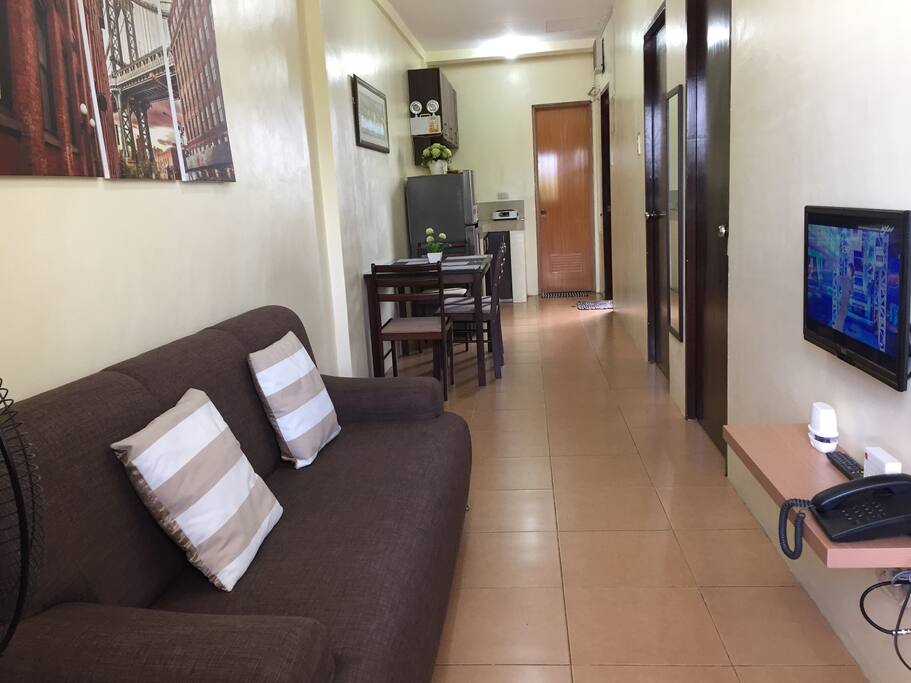 Living Area with long couch and smart tv, dining and kitchen area