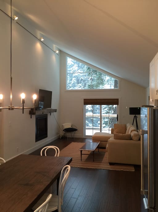 new flatscreen tv in light-filled living room opens to kitchen and deck