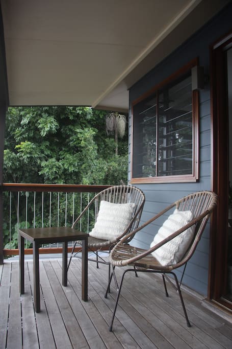 private balcony with view of stunning garden across the valley to byron bay lighthouse & ocean.