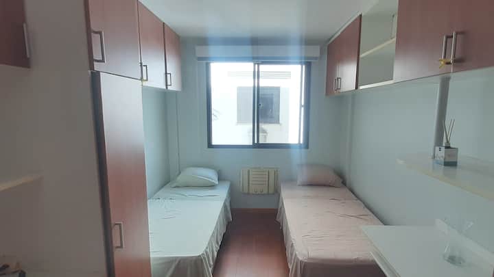 إطلالة على مدخل الغرفة بسريرين مفردين وسرير إضافي قابل للطي ومكيف هواء.