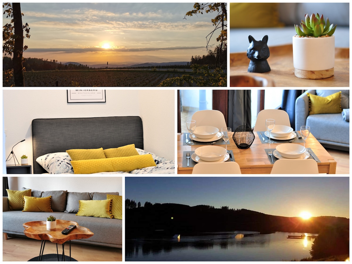 A serene landscape at sunset reveals rolling hills and a soft orange glow in the sky. A cozy interior features a comfortable gray sofa adorned with yellow pillows, complemented by a dining table set for four, and a decorative plant adds a touch of greenery.