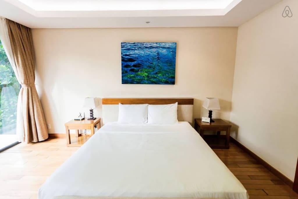 A bedroom decorated a double bed, a picture and 2 lamp. It seem to be simple but make an elegant feeling for guests