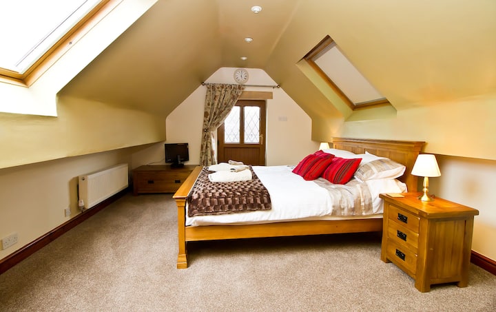 Ზემოთ საძინებელი მუხის დიდი ზომის საწოლით საკუთარი ტელევიზორით, რომელიც საკმარისია დამატებითი საწოლისთვის.