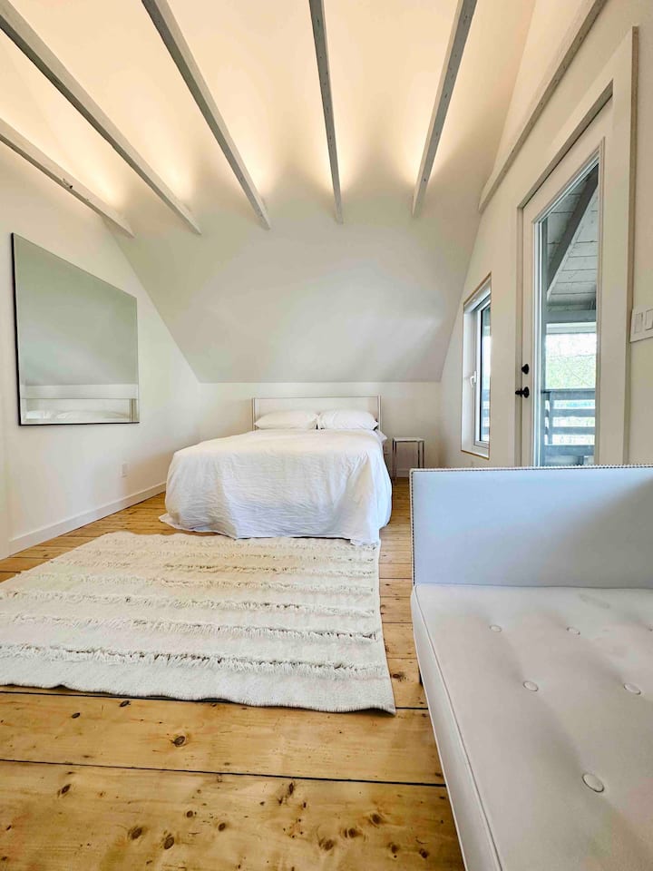 Large bedroom upstairs, with shades on windows and a balcony