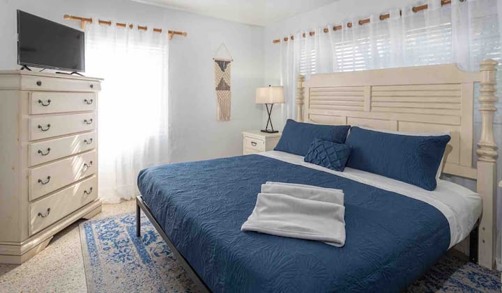 ¡Relájate en este dormitorio sereno con sábanas acogedoras, iluminación suave y un ambiente costero!