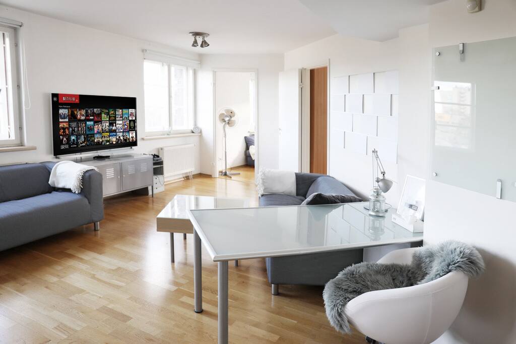 The main room features a wide work/eating table, comfortable sofas and a 55" LG Smart TV along with PlayStation 4 and Netflix.