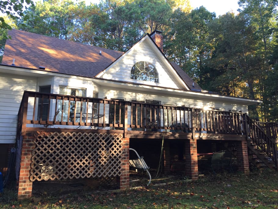 Back deck overlooks woodlands, with rockers and deck chairs.