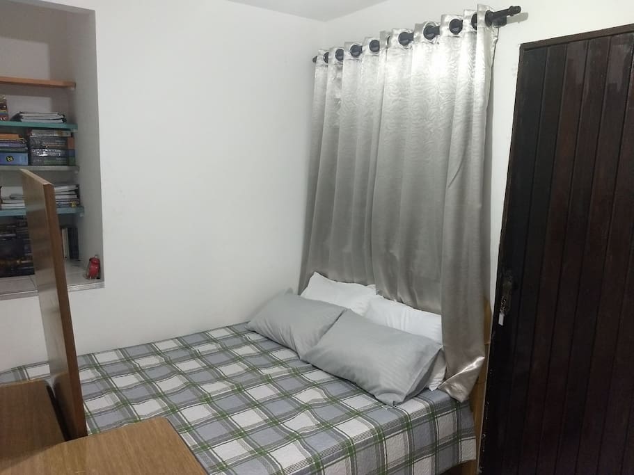 Vista da cama de casal, quarto espaçoso e bem iluminado.