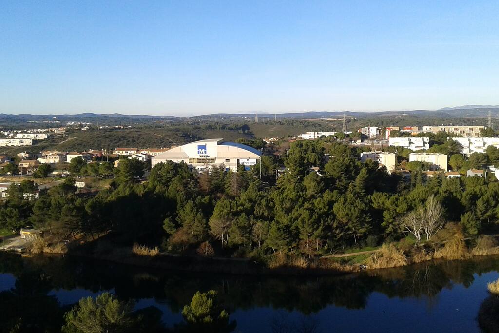 Chambre Sud-Ouest, vue plongeante sur le Lac des Garrigues (parc), le Palais des Sports et les collines