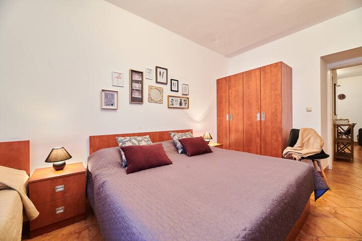Bedroom with a double bed and a single one, chair, wardrobe, bedside tables and night lamps