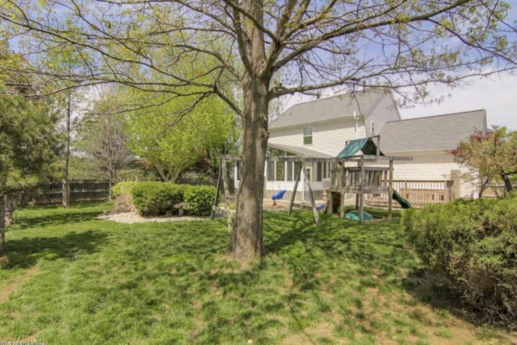 Large fenced backyard with swing set.
