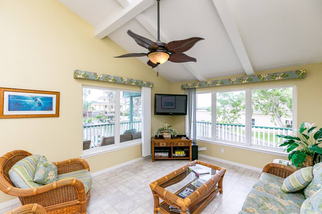 An airy living room features wicker furnishings and canal views.