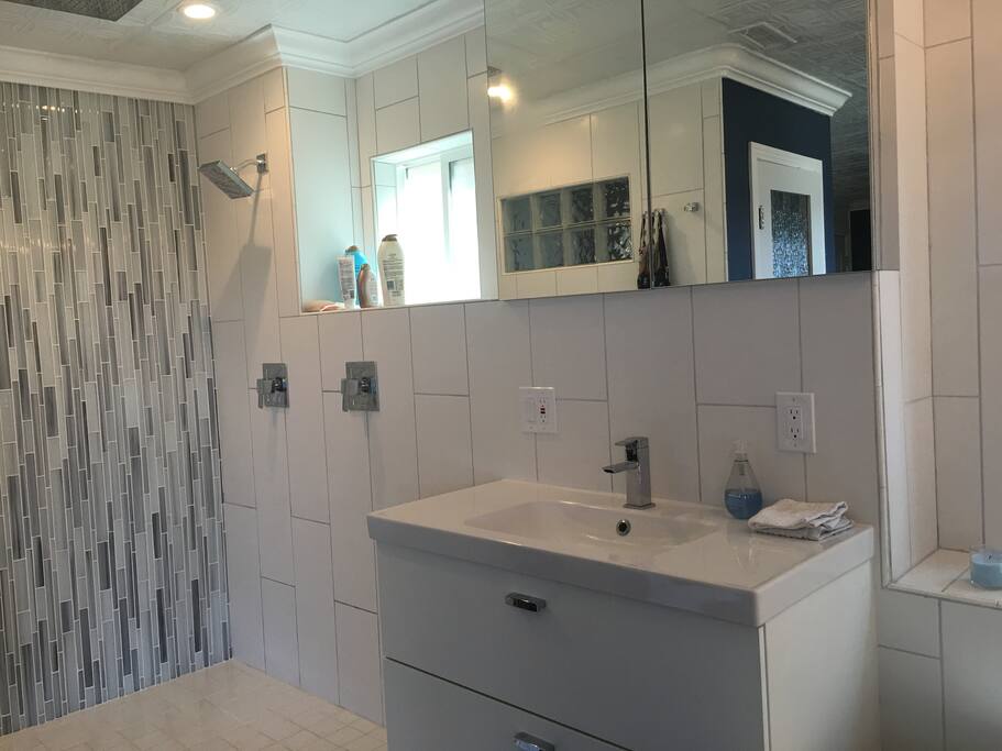 Walk in shower with rain shower head and wall shower head. Beautiful glass tile work, chrome fixtures. Shower has frosted window for privacy and air.