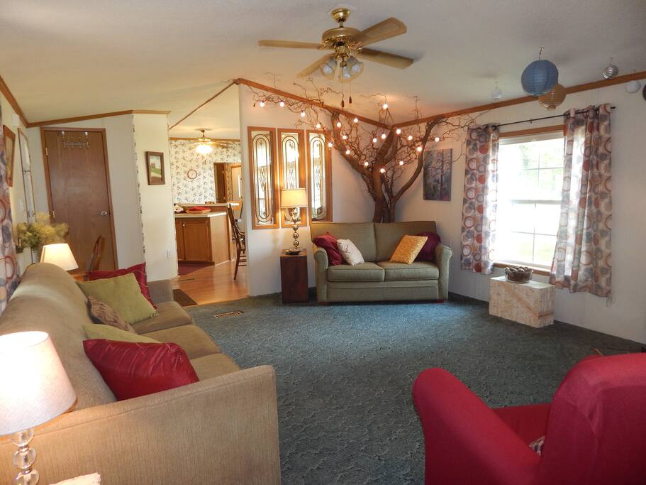 The living room flows into the kitchen and dining area. There's a "story book" tree in one corner. Both couches fold out into a queen-sized bed and a twin bed.