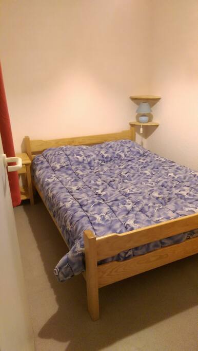 Chambre avec lit de 140 et armoire de rangement et patères, fermée par une porte. Possibilite de mettre un lit parapluie de 60 x 120 en décalant le lit vers la droite