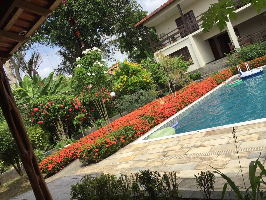 Piscina e amplo jardim, com chuveiro, cadeiras/mesas plásticas.