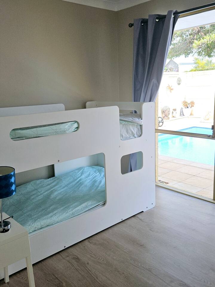 Vitanda vya ghorofa vyenye ukubwa kamili vilivyo na kabati la nguo na meza kando ya kitanda katika chumba cha kulala cha 3. 