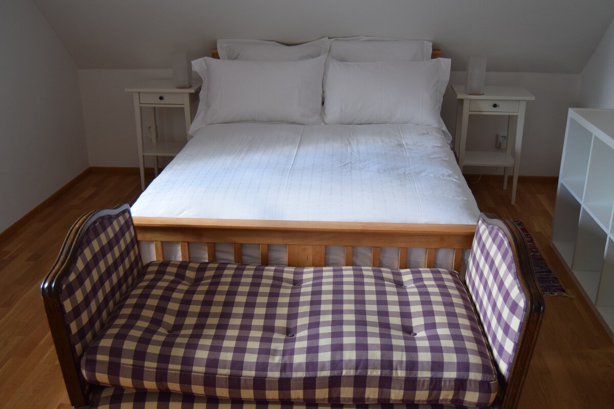 Cama tamaño king vestida con ropa de cama de 400 hilos; sofá para ver la televisión. Pasos hacia la derecha