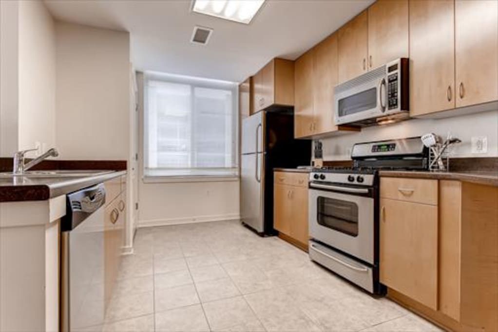 Fully equipped kitchen with stainless steel appliances, pots, pans and dishes