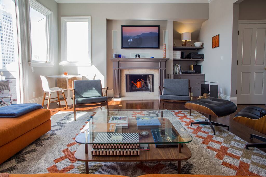 Living Room: plenty of natural light + Golden Gate Bridge view from the terrace on the left and the breakfast table in the corner; fireplace, vintage danish chairs, design furniture and hifi system (from analog to digital: turntable to AppleTV). The door you see on the right is the small elevator, next to the stairs.